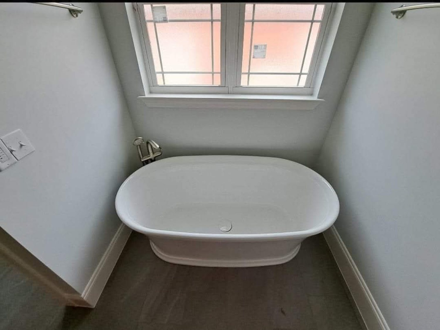 Freestanding white bathtub beneath a window