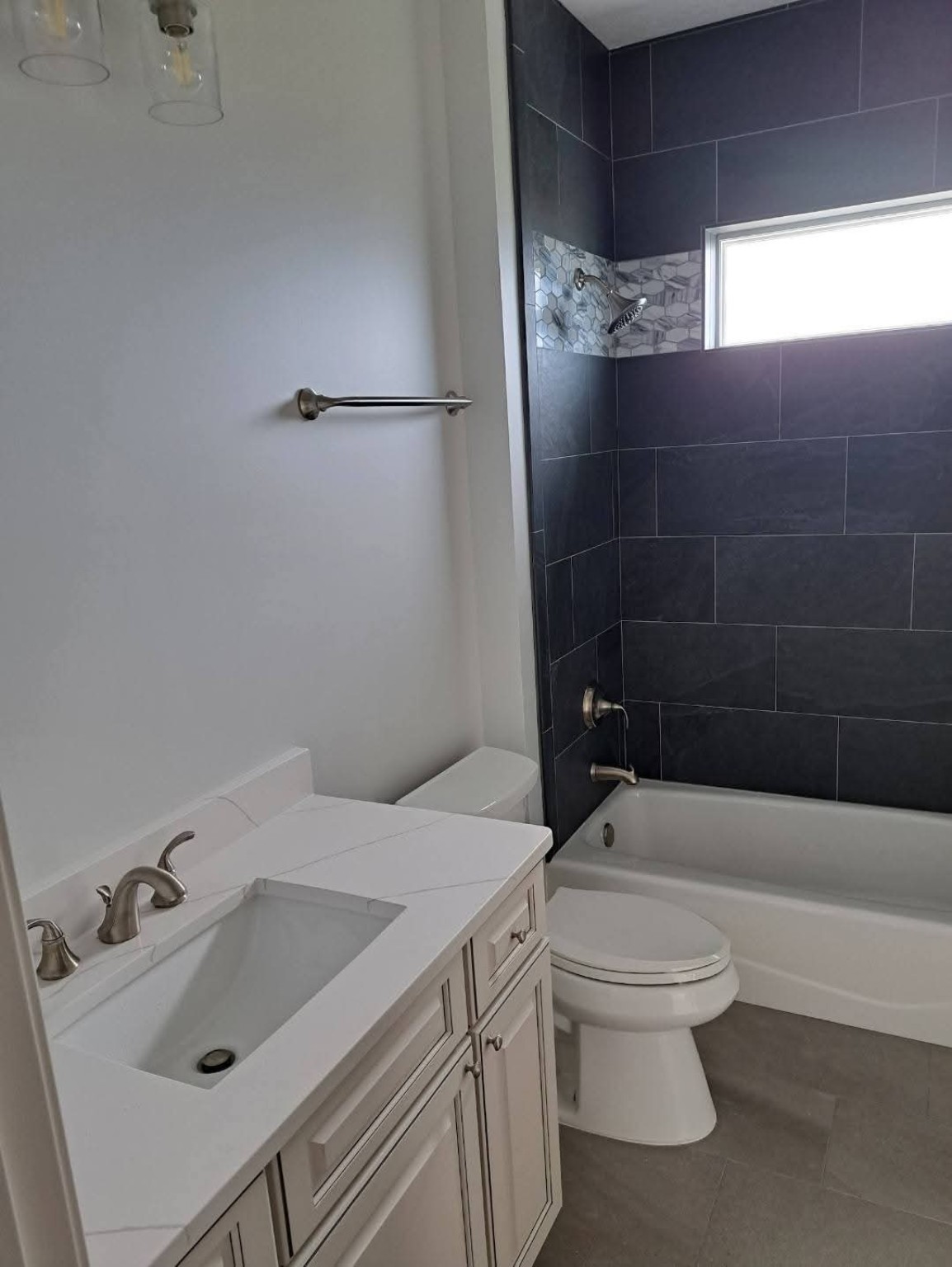 Modern bathroom with tiled tub shower, vanity and toilet