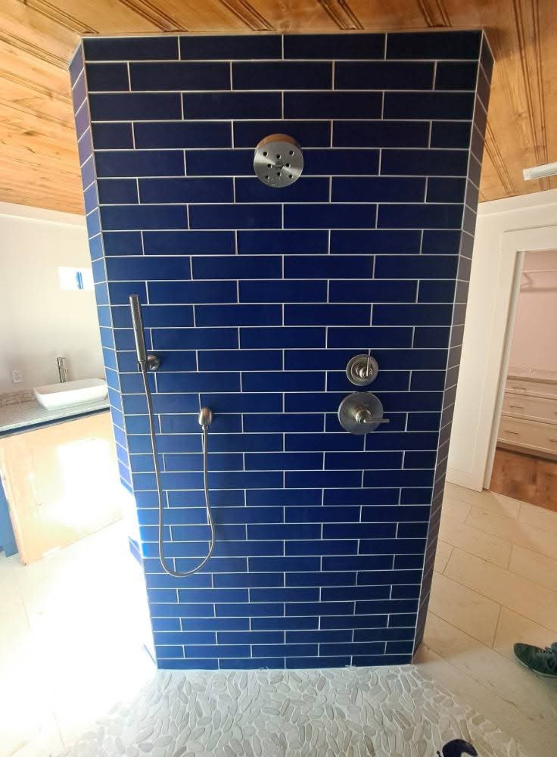Walk-in shower with deep blue tile and handheld shower