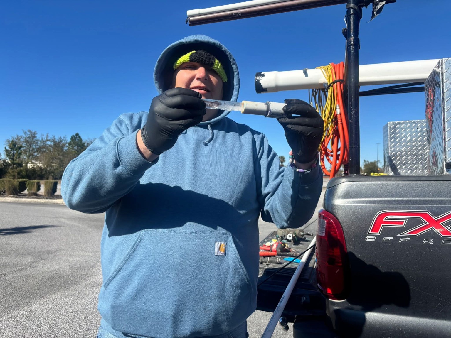 Plumbing team member demonstrating a frozen water pipe beside service truck