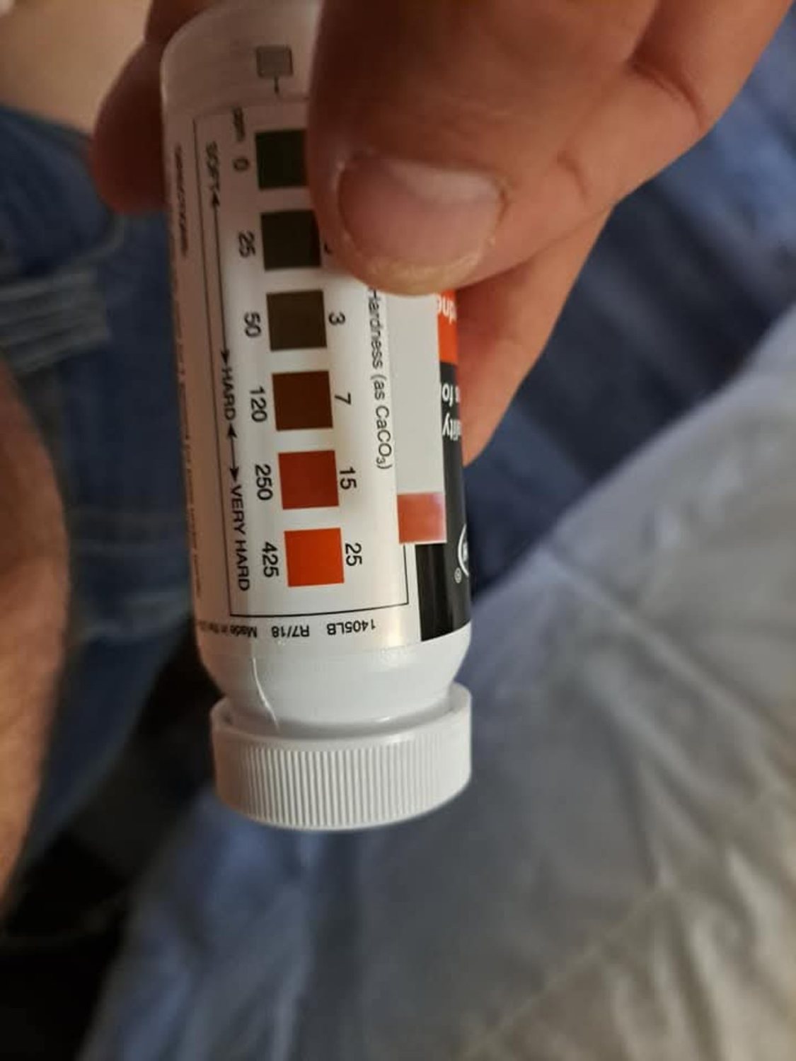 Water hardness test strip compared with a color scale